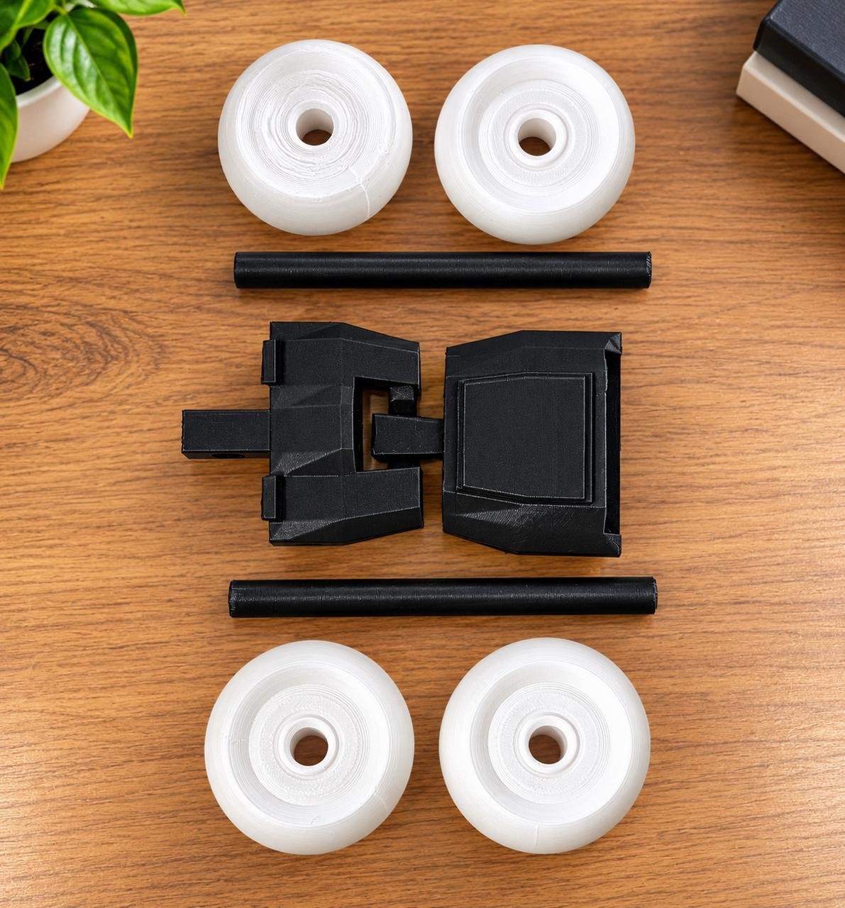 Black 3D printed stunt car with white oversized wheels on a wooden desk setup